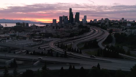 Roadtrip-Aerial-of-Cars-Traveling-from-City-on-Freeway-for-Night-Drive-with-Sunset-Afterglow