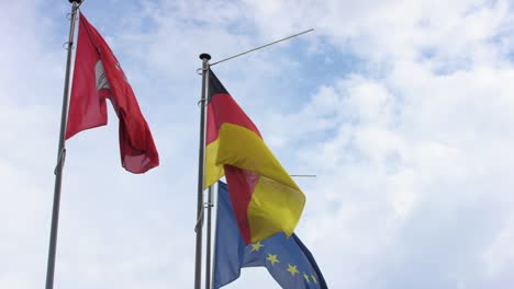 Blick-auf-deutschen-und-europäischen-Flagge,-die-leichte-Brise-vor-blauem-Himmel