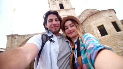 Young-tourists-taking-a-smiling-selfie-in-picturesque-stonebuilt-village