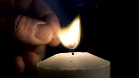 Slow-motion-macro-footage-of-a-white-candle-lit-by-a-match-on-a-dark-background