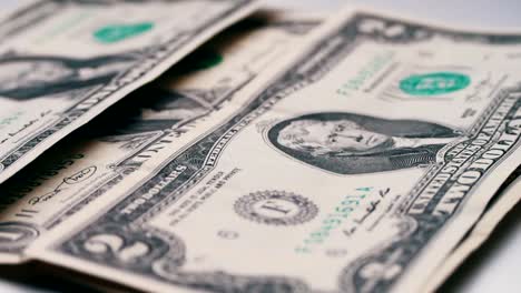 lot-of-small-dollar-bills-fall-on-the-table-with-a-white-background-macro-close-up