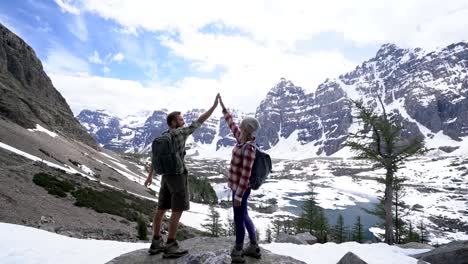 Pareja-senderismo-en-las-montañas-Rocosas-canadienses-llegar-a-la-cima-de-la-montaña-y-dar-un-alta-cinco-para-celebrar