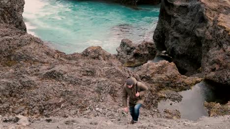 Young-handsome-man-hiking-alone.-Traveling-male-walking,-climbing-through-the-hill-near-the-blue-lake-alone