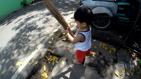 Bebé-de-niño-de-dos-años-barriendo-la-calle-con-una-escoba