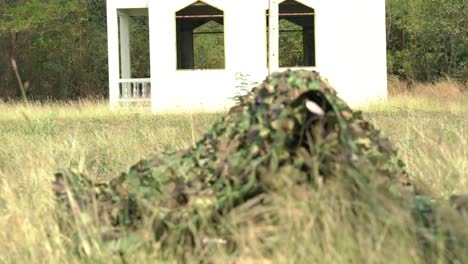 Sniper-soldier-lying-on-the-ground-and-camouflage-in-grass.-Soldier-holding-gun-weapon-and-waring-armor-uniform.-The-military-is-responsible-for-maintaining-the-territory.