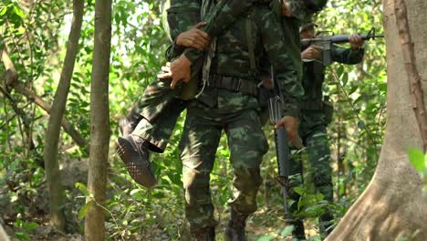 Soldier-holding-gun-weapon-and-waring-armor-uniform-with-smoke.-Soldiers-are-taking-the-wounded-man-out-of-the-jungle.