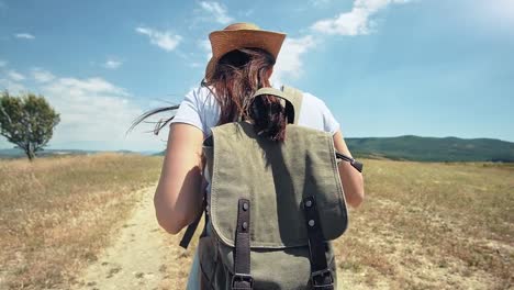 Female-European-traveler-with-backpack-on-the-trail-of-dried-field-at-trekking-lifestyle-trip