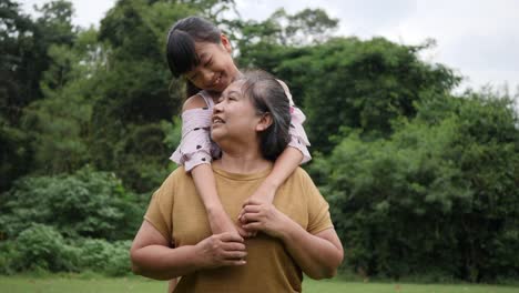 Slow-motion-of-Happy-grandmother-with-granddaughter-playing-in-the-park