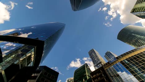 Bottom-up-Blick-auf-rotierende-Wolkenkratzer-und-fliegenden-Wolken,-Zeitraffer,-hyper-Zeitraffer