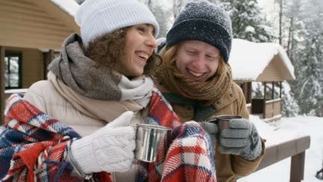 Lachend-paar-Teetrinken-im-Freien-im-Winterwald