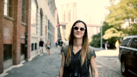 Cámara-sigue-a-chica-turista-europeo-emocionado-feliz-con-mochila-y-cámara-en-las-gafas-de-sol-sonriente,-girando-alrededor-de-4K