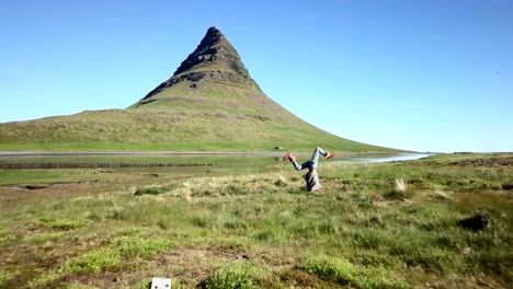 Drone-point-of-view-of-Young-woman-exercising-yoga-headstand-pose-in-pure-nature,-Iceland.-People-travel-healthy-lifestyle-and-yoga-concept--4K-video