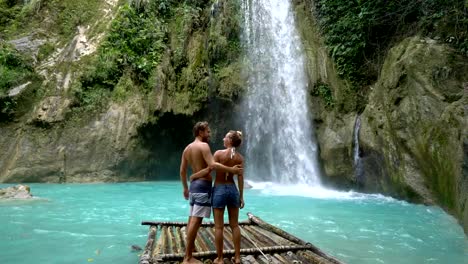 Young-couple-being-affectionate-at-beautiful-tropical-waterfall-in-the-Philippines-enjoying-vacations-and-freedom.-People-travel-love-concept