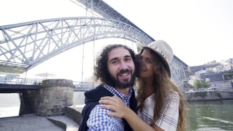 Paar-lustige-Selfie-am-Ufer-in-der-Nähe-von-Brücke-unter