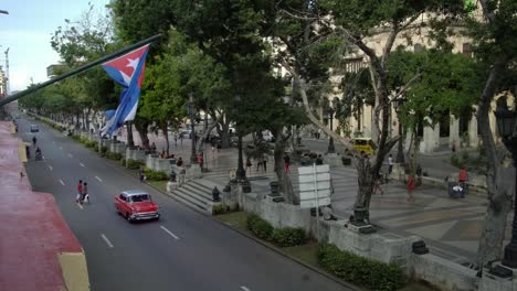 Coches-clásicos-en-la-calle-de-la-Habana-vista-desde-arriba,-la-bandera-cubana-en-La-Habana,-Cuba