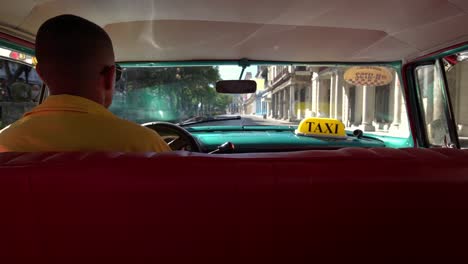 Taxifahrer-in-klassische-amerikanische-1950-Oldtimer-Fahrt-auf-der-berühmten-Straße-im-alten-Viertel-der-Havanna,-Kuba