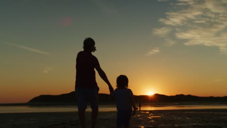 Silueta-del-padre-y-el-hijo-caminando-juntos-en-la-playa