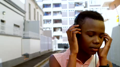 Woman-listening-music-on-headphones-while-walking-in-city-street-4k