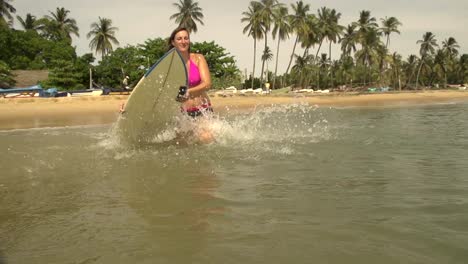 Weibliche-surfer-Sprünge-auf-dem-Surfbrett-und-beginnt-Paddeln