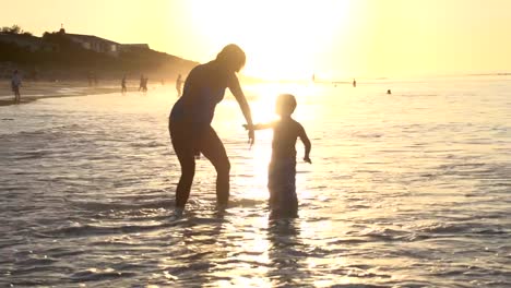 Mutter-und-Kind-spielen-am-Strand-auf-silhouette-bei-Sonnenuntergang,-Cape-Town