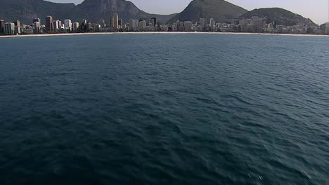 Low-angle-flight-above-the-ocean-to-reveal-Ipanema-Beach