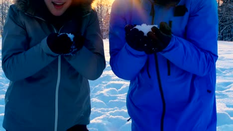 Couple-blowing-snow-in-snowy-forest