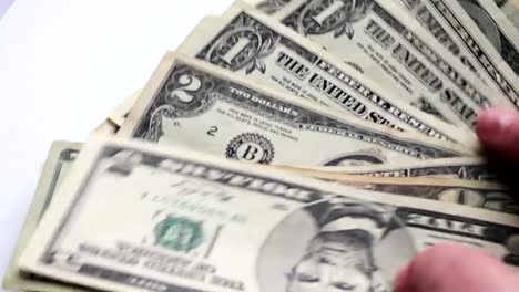 Woman-countslot-of-small-dollar-bills-on-the-table-with-a-white-background-macro-close-up