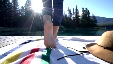 Cerrado-en-los-pies-de-la-mujer,-caminando-sobre-un-muelle-de-madera-sobre-el-impresionante-paisaje-de-lago-en-el-corazón-de-las-Rocosas-canadienses