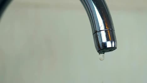 Close-up-a-droplets-of-water-drip-from-the-aluminum-tap-in-the-kitchen-at-home.-4K.