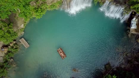 Drone-shot-aerial-view-of-young-woman-lying-down-like-star-shape-on-bamboo-rafting-at-tropical-waterfall.-4K-resolution-video,-shot-in-the-Philippines.-People-travel-fun-vacations-adventure-concept