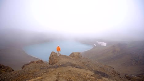 4K-Young-woman-in-Iceland-contemplating-crater-volcanic-lake-from-top-of-it