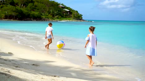 Kleinen-niedlichen-Mädchen-spielen-mit-Kugel-am-Strand