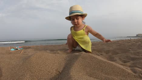 Niedliche-Mädchen-spielen-mit-Sand-am-tropischen-Strand