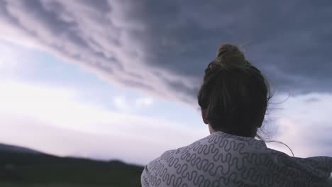 Junge-Frau-in-Decke-Stand-auf-dem-Balkon,-die-Aussicht-auf-dramatische-Wolken-Nahaufnahme-Schuss