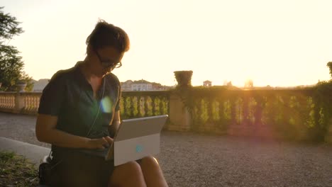 Estudiante-de-la-hermosa-joven-en-balcón-alto-en-campidoglio-escribir-trabajo-en-ordenador-portátil-frente-a-paisaje-urbano-de-Roma-al-atardecer-ver-históricos-edificios-y-cúpulas-lenta-steadycam