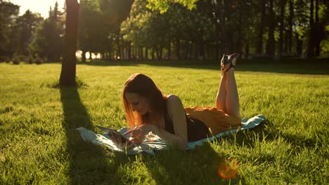 Mädchen-sitzen-im-Park-unter-den-Bäumen-und-nutzen-Sie-das-Internet-auf-tablet