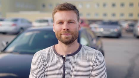 Retrato-de-un-hombre-exitoso-en-su-coche-en-el-estacionamiento-exterior-de-pie-y-sonriendo