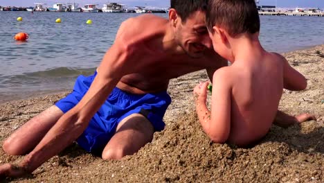 Young-father-with-a-small-son-on-a-sea-beach,-Greece