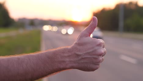 Man-hand-close-up-thumb-up,-hitchhiker-on-road-try-to-catch-car