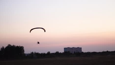 Der-Pilot-auf-einem-Gleitschirm-fliegt-in-den-Himmel-über-Sonnenuntergang-und-Nacht-Landschaft.-Hintergrund