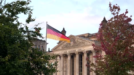 Reichstag-und-deutsche-Flagge,-umrahmt-von-Bäumen-in-Berlin,-Deutschland