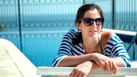 Hermosa-mujer-Europea-de-gafas-de-sol-acostado-en-la-silla-de-cubierta-con-los-brazos-cruzados-disfrutando-del-sol