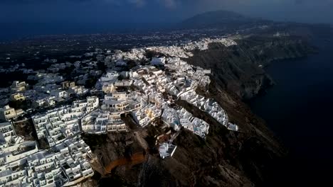 Sobrevuelo-de-pueblo-de-Imerovigli-y-roca-Skaros-en-puesta-del-sol,-isla-de-Santorini,-Grecia