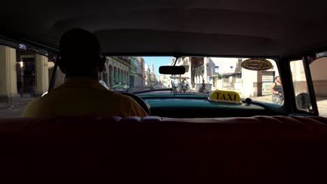 Taxi-driver-in-classic-American-1950's-vintage-car-drive-on-famous-street-in-old-Havana-neighborhood,-Cuba