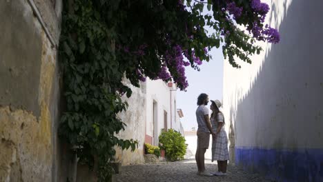 Pareja-besándose-entre-viejos-edificios-cerca-de-arbusto-con-flores