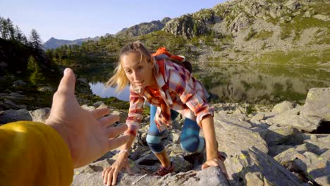 Teammate-helping-hiker-to-reach-summit-.-Couple-hiking-in-Switzerland,-hand-reach-out-to-help-female-hiker-reach-the-summit.-A-helping-hand-concept