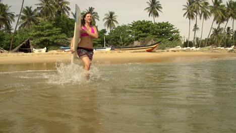 Weibliche-surfer-Laufen-ins-Wasser-und-beginnt-Paddeln