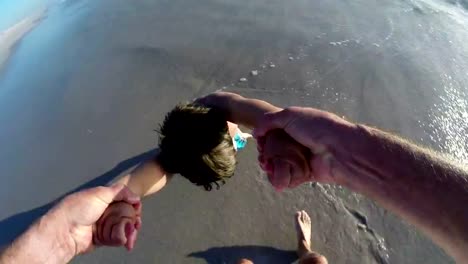 POV-of-Father-swinging-happy-child-on-beach,Cape-Town