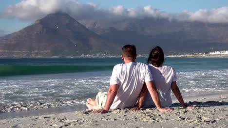 Couple-sitting-close-together-on-beach-and-enjoying-the-view,South-Africa