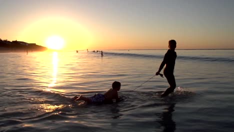 Zwei-Jungen-spielen-am-Strand-im-silhouette-bei-Sonnenuntergang,-Cape-Town